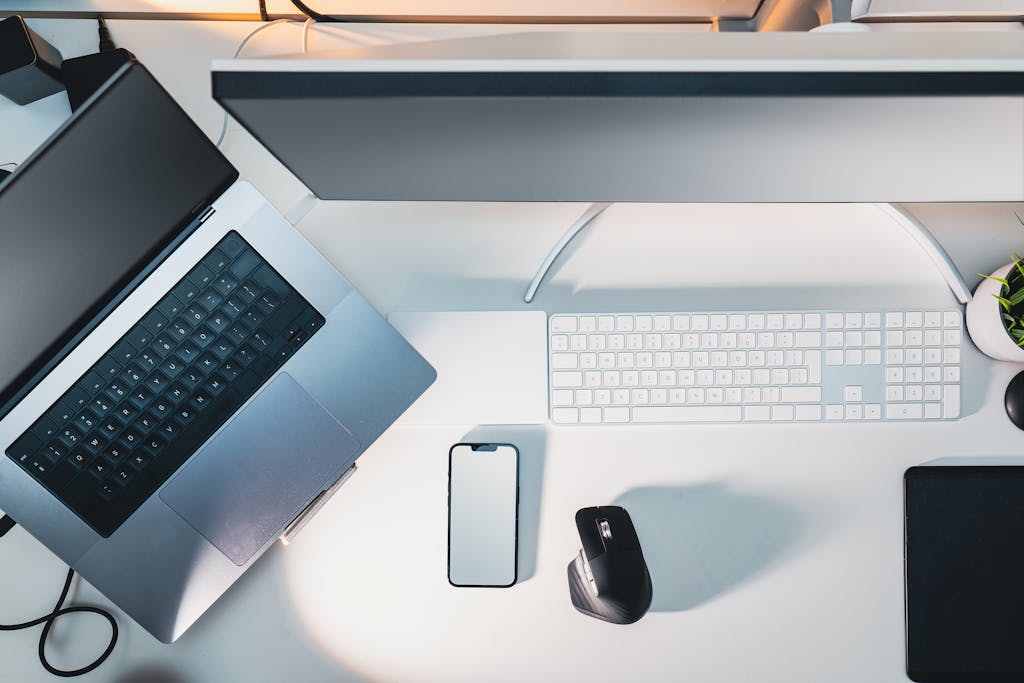 Clean and organized modern workspace featuring laptop, smartphone, and monitor.